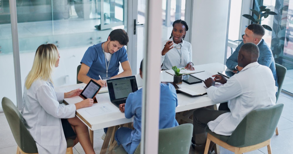A group of doctors and researchers meet around a table reviewing data and treatment plans for cancer immunotherapy.