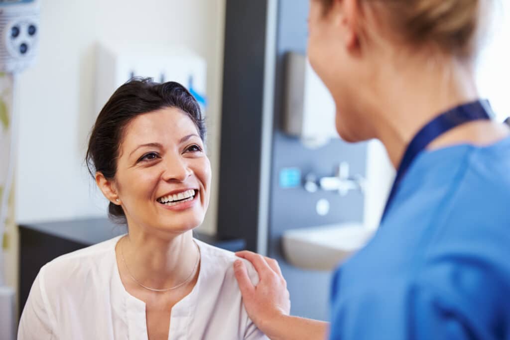 Smiling patient speaking with a healthcare professional, representing compassionate support and positive outcomes from cancer research advancements.